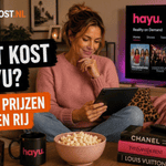Sanne zit met opgetrokken benen op een bank in een stijlvolle woonkamer en houdt een tablet vast. Op de achtergrond staat hayu op een televisie en links staat de titel ‘Wat kost Hayu?’ in de herkenbare Ditkost.nl-stijl.