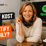 Persoon met een zwarte hoofdtelefoon om de nek kijkt recht in de camera vanuit een woonkamer. Links staat de tekst “Wat kost een Spotify Family?” in de Ditkost.nl-stijl en op de achtergrond is een Spotify-logo zichtbaar op een televisiescherm.